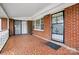 Covered front porch featuring tile flooring, brick walls, and black iron security door and white railing at 800 Old Little Rock Rd, Charlotte, NC 28214