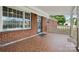 Charming covered front porch boasts red tile flooring, brick detail, black security door, and white railing at 800 Old Little Rock Rd, Charlotte, NC 28214