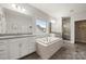 Bright bathroom with a soaking tub, double vanities, granite counters, and wood tile floor at 9530 Hightower Oak St, Huntersville, NC 28078