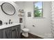 Modern bathroom features a vanity with dark gray cabinets and a decorative round mirror at 9530 Hightower Oak St, Huntersville, NC 28078