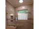 Modern walk-in shower featuring neutral-toned tiles, glass door, window with curtain, and rainfall shower head at 1000 E Woodlawn Rd # 107, Charlotte, NC 28209