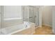Bright bathroom featuring soaking tub, walk-in shower with glass door, and a window providing natural light at 1030 Pinehurst Ln, Fort Mill, SC 29707