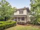 An idyllic property showcasing a covered porch, lush greenery, and serene surroundings at 1120 N College St, Mount Pleasant, NC 28124
