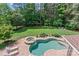 Aerial view of a backyard oasis with a swimming pool, hot tub, lush lawn, and surrounding trees at 129 Alder Springs Ln, Mooresville, NC 28117
