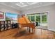 Elegant living room featuring a grand piano, coffered ceiling, and sliding doors to the pool area at 129 Alder Springs Ln, Mooresville, NC 28117