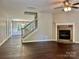 Inviting living room featuring a stone fireplace, hardwood floors, and an open staircase at 13913 Pinyon Pine Ln, Charlotte, NC 28215