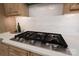 Close-up of a modern gas cooktop set in a white countertop with subway tile backsplash at 14515 Nolen Ln, Charlotte, NC 28277