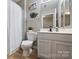 Well-lit bathroom featuring a toilet, vanity with sink and a shower with white curtain at 15639 Sir Charles Pl, Charlotte, NC 28277