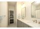 Bright bathroom featuring double sink vanity with framed mirrors, soft gray cabinetry, and open doorway to bedroom at 1638 Myers Park Dr, Charlotte, NC 28207