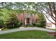 Brick home featuring a manicured lawn, mature trees, a curved driveway and a covered front entry at 1638 Myers Park Dr, Charlotte, NC 28207