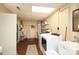 Well-lit laundry room with white washer and dryer, utility sink, shelving, and storage space at 1638 Myers Park Dr, Charlotte, NC 28207