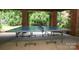 Covered outdoor patio area featuring a ping pong table and brick columns with lush landscaping views at 1638 Myers Park Dr, Charlotte, NC 28207