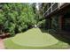 Backyard putting green with artificial turf, flags, and seating area, surrounded by mature landscaping at 1638 Myers Park Dr, Charlotte, NC 28207