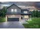 Charming two-story home with a brick facade, black garage door, and well-manicured lawn at dusk at 207 9Th Ne Ct, Conover, NC 28613