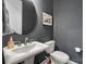 Stylish powder room with a pedestal sink, round mirror, and dark gray walls at 310 N Dotger N Ave # 4, Charlotte, NC 28204