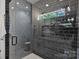 Modern bathroom featuring a gray subway tile shower with glass door, built-in niche, and double vanity at 3163 Maury St, Charlotte, NC 28208