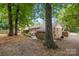 Brick home featuring an outdoor patio, well-maintained landscaping, and mature trees at 3900 Langley Rd, Charlotte, NC 28215