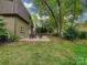 Lush backyard with a cozy patio featuring a seating area under the shade of mature trees at 4025 Woodfox Dr, Charlotte, NC 28277