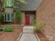 A cozy front entrance with a red door, brick facade, and landscaped walkway at 4025 Woodfox Dr, Charlotte, NC 28277