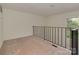An upstairs loft area featuring neutral carpet, black railing, and natural light from a window at 4025 Woodfox Dr, Charlotte, NC 28277