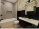 Stylish bathroom featuring gray tiled walls, black accents, and a modern vanity with a decorative leaf wallpaper accent at 415 S Boyd St, Gastonia, NC 28052