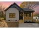 Charming single-Gathering home featuring a covered front porch, neutral siding, and dark trim against a beautiful sunset at 415 S Boyd St, Gastonia, NC 28052