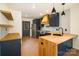 Modern kitchen boasts navy cabinets, wood countertops and accents, stainless steel appliances, and floating shelves at 415 S Boyd St, Gastonia, NC 28052
