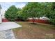 Large backyard featuring a concrete patio, grass, and mature trees with a wood fence perimeter at 4658 Cedar Rock Dr, Charlotte, NC 28273