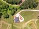 Aerial view of a home featuring manicured lawns, a pond, and a circular driveway, set amidst a wooded landscape at 534 N Ingleside Farm Rd, Iron Station, NC 28080