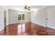 Sun-drenched bedroom with gleaming hardwood floors, neutral paint, a ceiling fan, and large window at 534 N Ingleside Farm Rd, Iron Station, NC 28080