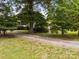 Secluded home surrounded by mature trees and a gravel driveway leading to the house at 5371 Davidson Rd, Davidson, NC 28036