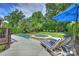 Relaxing pool and spa with striped lounge chairs and blue umbrella in a private, tree-lined backyard at 7428 Edenbridge Ln, Charlotte, NC 28226
