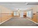 Spacious living room with neutral carpet, wood paneled walls, ceiling fan, and natural light at 1000 Peachtree Rd, Charlotte, NC 28216