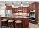 Well-equipped kitchen with cherry cabinets, stainless steel appliances, a granite countertop island and pendant lighting at 10502 Old Ardrey Kell Rd, Charlotte, NC 28277