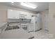 Well-lit kitchen featuring white appliances and cabinets, and tiled flooring for a clean, classic look at 112 Dujon Ct, Mount Holly, NC 28120