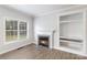 Cozy living room with hardwood floors, fireplace, built-in shelving, and large windows at 11526 Mcginns Trace Ct, Charlotte, NC 28277