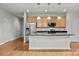 Open kitchen with stainless appliances, island with seating, and wood floors at 120F Steinbeck Way, Mooresville, NC 28117