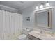 Well-lit bathroom featuring a white shower curtain, a classic vanity, and a decorative mirror at 1402 Coachman Dr, Waxhaw, NC 28173