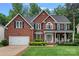Charming two-story red brick home featuring a well-manicured lawn, attached garage, and inviting front porch at 1402 Coachman Dr, Waxhaw, NC 28173