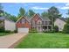 Charming two-story red brick home featuring a well-manicured lawn, attached garage, and inviting front porch at 1402 Coachman Dr, Waxhaw, NC 28173
