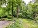 Lush backyard featuring mature trees, green grass, and a partially wooded area for privacy at 2401 Wensley Dr, Charlotte, NC 28210