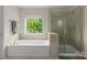 Bright bathroom showcasing a soaking tub, tiled shower, and large window offering a serene and relaxing atmosphere at 2606 Walker Rd, Matthews, NC 28105