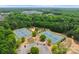Aerial view of tennis courts and parking lot surrounded by trees and nearby community at 2606 Walker Rd, Matthews, NC 28105