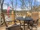 A cozy deck with a bistro table and two chairs overlooks a serene lake and an American flag at 3115 Duck Point Dr, Monroe, NC 28110