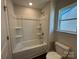 Clean bathroom with a tub-shower combination, storage shelves, and a window, providing a functional space at 4131 Black Ct # 170, Harrisburg, NC 28075