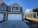 Two-story townhome features stone accents, a two-car garage, and an 'available' sign in the upper window at 4131 Black Ct # 170, Harrisburg, NC 28075