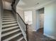 Staircase with dark wood and metal railing leading to a view of the kitchen with white cabinets at 4131 Black Ct # 170, Harrisburg, NC 28075
