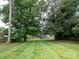 Expansive backyard featuring lush green grass, mature trees, and a storage building at 557 Melbourne Ct, Charlotte, NC 28209
