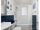 Bright bathroom features a shower-tub combination, a modern vanity and blue wall panelling, plus natural light at 557 Melbourne Ct, Charlotte, NC 28209