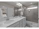 Modern bathroom with double sinks, white cabinets, and a walk-in shower featuring gray tile at 5625 Axil Ln, Charlotte, NC 28269